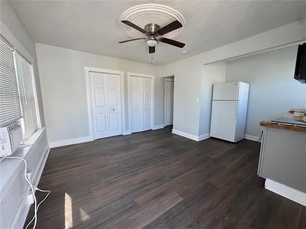 a view of room with wooden floor and a ceiling fan