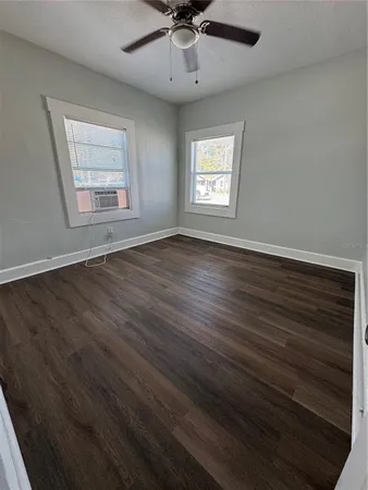an empty room with wooden floor chandelier and windows