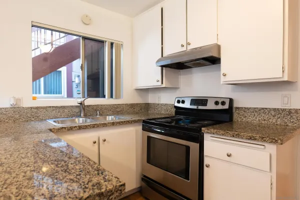 a kitchen with granite countertop a sink a stove and cabinets