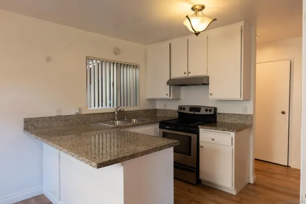 a kitchen with granite countertop a sink a stove and cabinets
