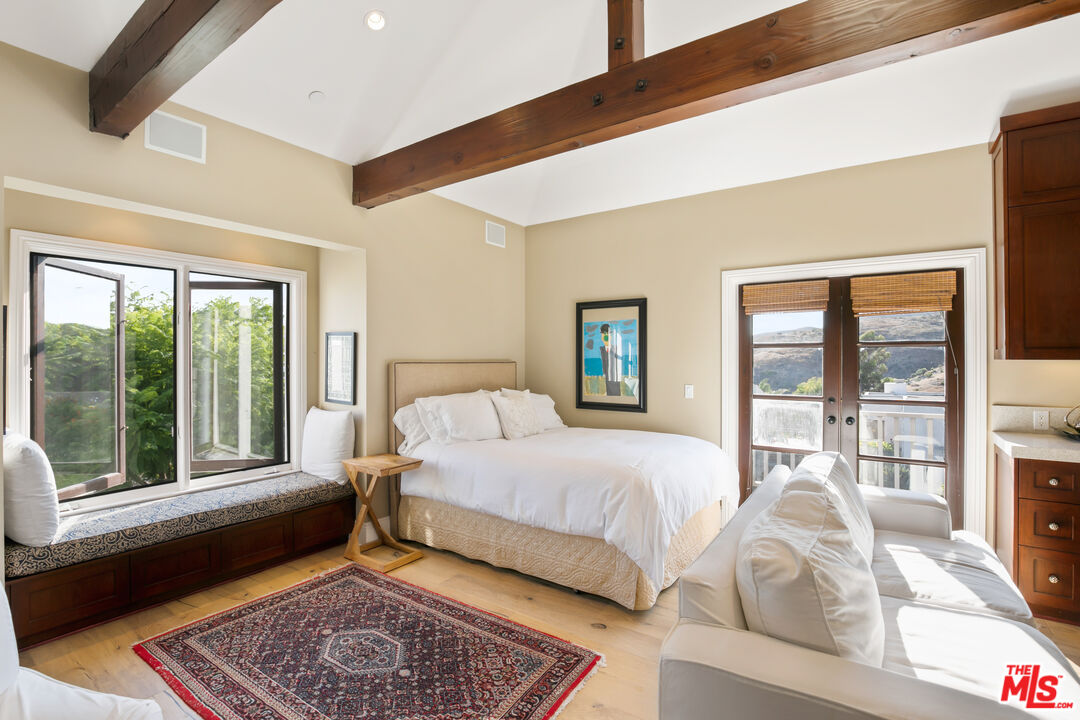 2962 Valmere Drive Malibu, CA 90265 - Photo 20 of 50 a bedroom with a bed lamp and a large window with outer view