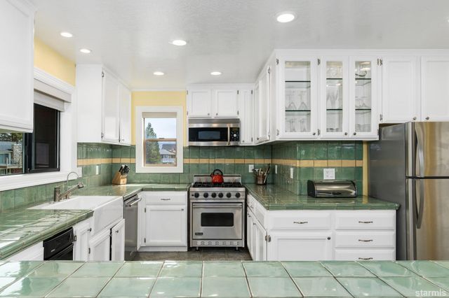a kitchen with stainless steel appliances granite countertop a stove top oven a sink and a refrigerator