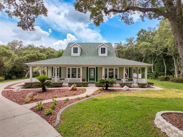a front view of a house with garden and trees
