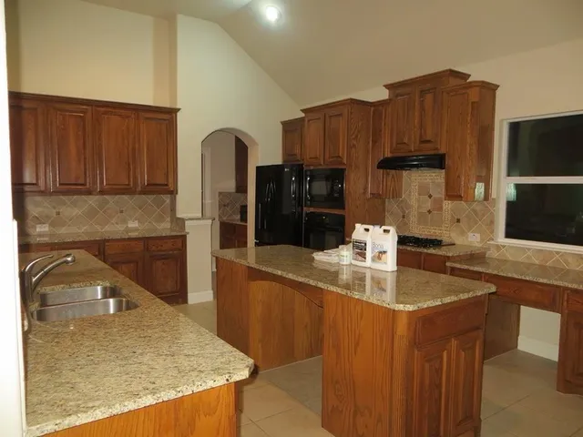 a kitchen with kitchen island granite countertop a sink a stove and cabinets