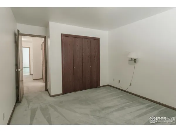 a view of an empty room with closet and a window