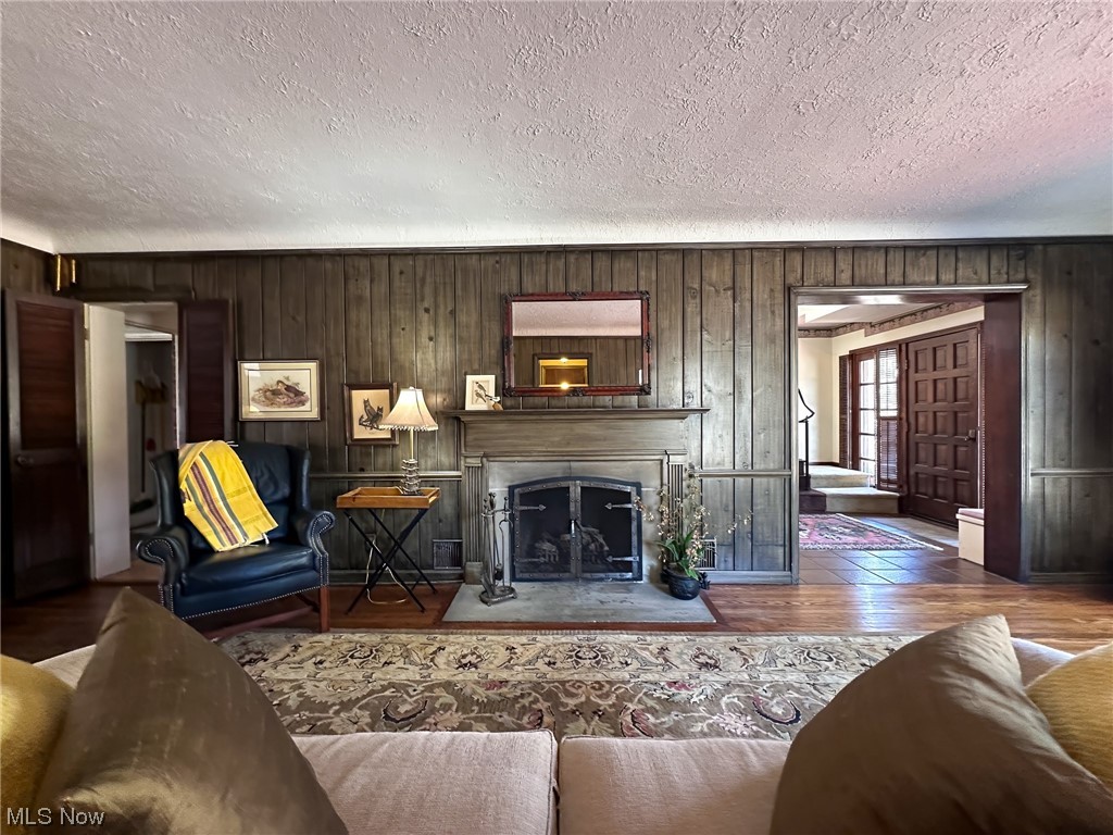 11911 County Line Road Chesterland, OH 44026 - Photo 7 of 49 Living room featuring dark hardwood / wood-style floors, wood walls, and a textured ceiling