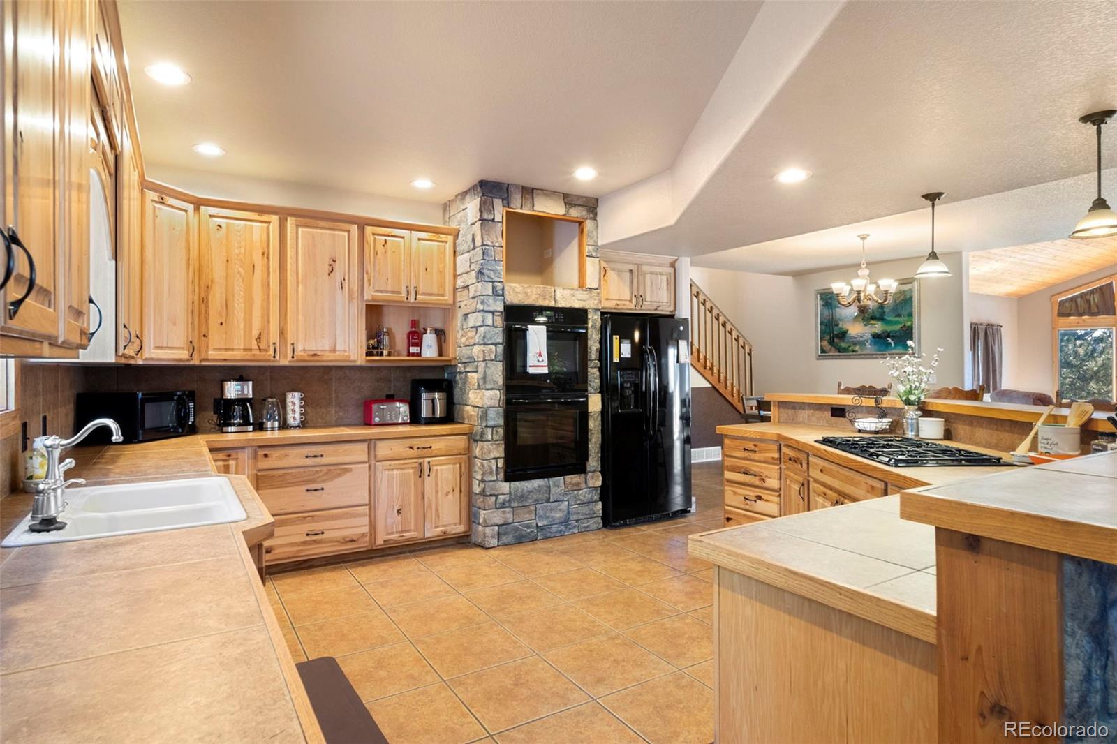 412 Evergreen Road Black Hawk, CO 80422 - Photo 15 of 48 a large kitchen with stainless steel appliances kitchen island granite countertop a refrigerator and a stove top oven