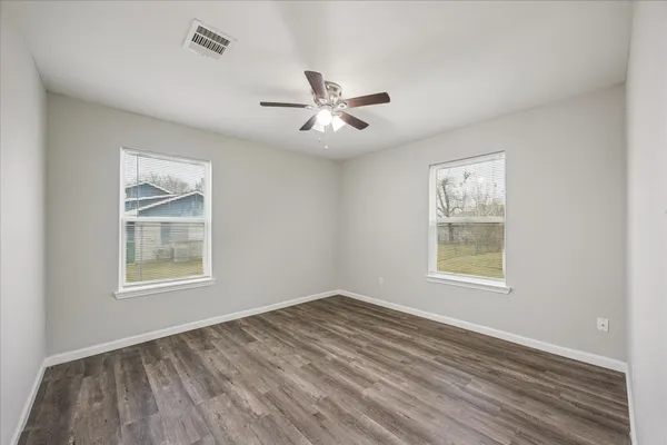 a view of an empty room with a window and wooden floor