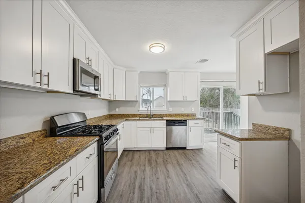 a kitchen with stainless steel appliances granite countertop wooden cabinets stove top oven and sink