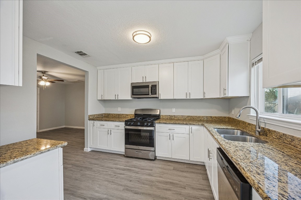 5126 Higgins Street Houston, TX 77033 - Photo 7 of 14 a kitchen with granite countertop a sink a stove top oven and cabinetry