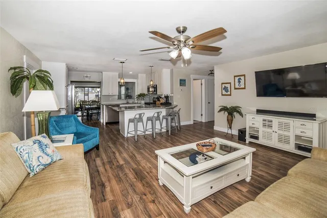a living room with furniture a flat screen tv and kitchen view