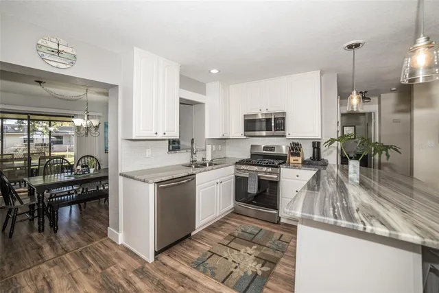 a kitchen with granite countertop a stove top oven a sink dishwasher a dining table and chairs with wooden floor