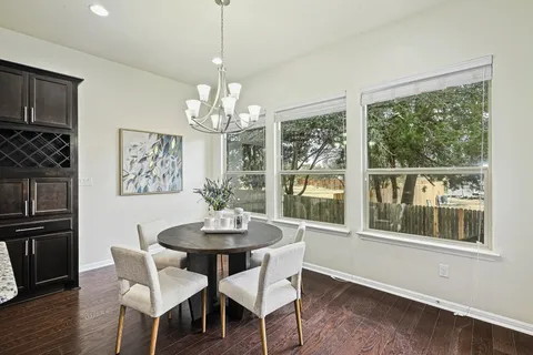 a view of a dining room with furniture large window wooden floor and chandelier