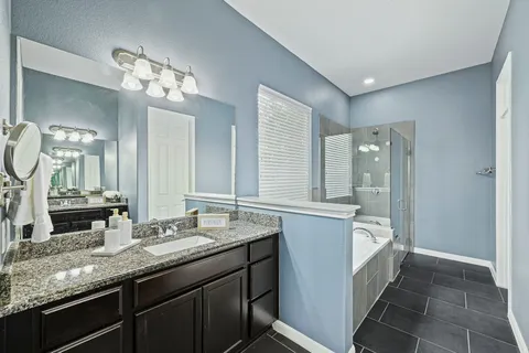 a bathroom with a granite countertop double vanity sink a mirror and shower