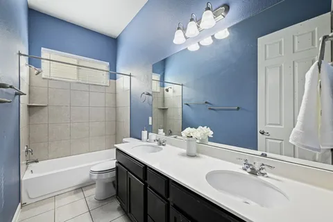 a bathroom with a double vanity sink a toilet a shower and a mirror