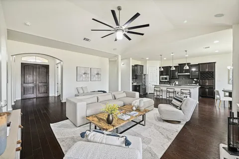 a living room with furniture kitchen view and a wooden floor