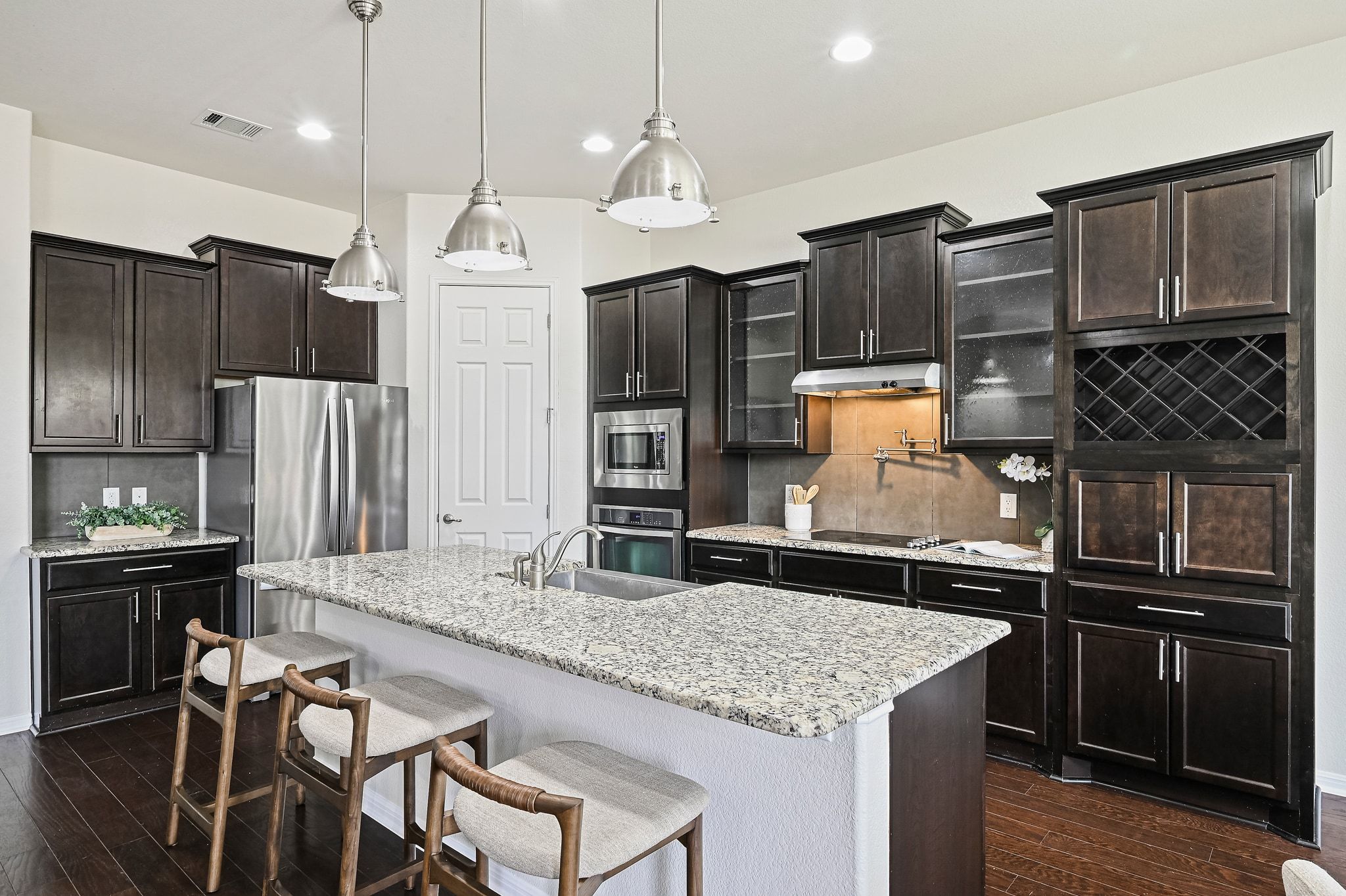 803 Wilson Ranch Place Cedar Park, TX 78613 - Photo 8 of 32 Deep espresso cabinetry adorns the kitchen, featuring glass front accents and wine storage.