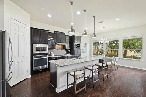 a kitchen with stainless steel appliances granite countertop a stove refrigerator and a view of living room