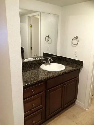 a bathroom with a granite countertop sink and a mirror