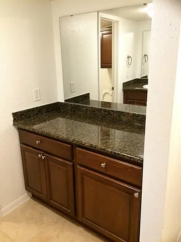 a bathroom with a granite countertop sink and a mirror