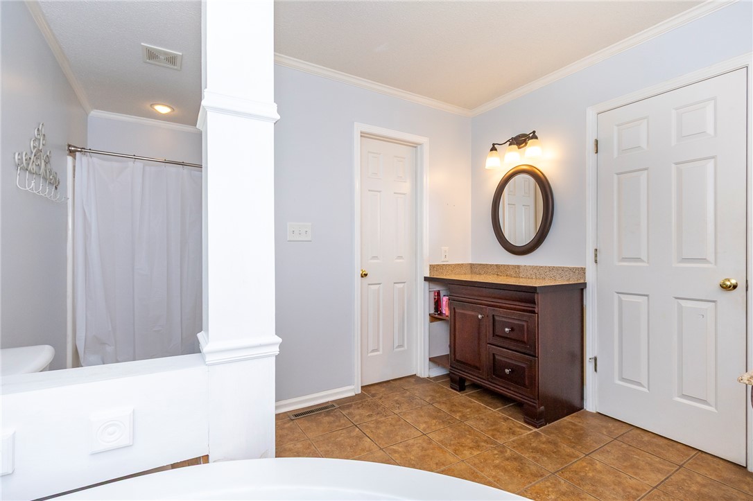 151 Hannah Circle Anderson, SC 29621 - Photo 18 of 46 This primary bathroom features a shower with a privacy curtain and a stylish vanity with a granite countertop.