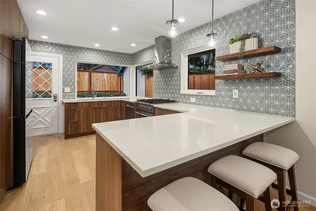 a kitchen with stainless steel appliances granite countertop a sink a stove a refrigerator a microwave oven with white cabinets and wooden floor