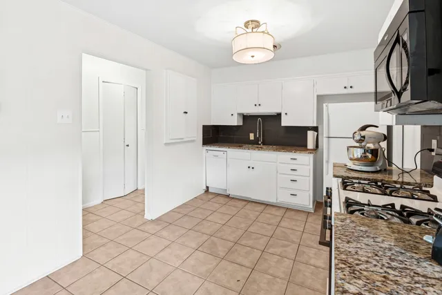 a kitchen with granite countertop a sink a stove and cabinets