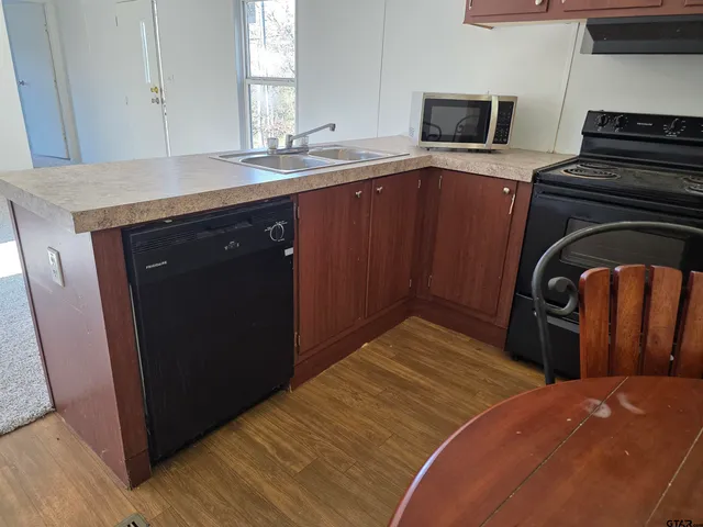 a kitchen with stainless steel appliances granite countertop a refrigerator a sink and wooden cabinets