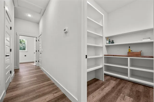 an empty room with wooden floor chandelier fan and windows