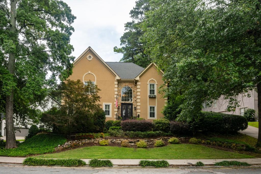 a view of house with garden and tall trees