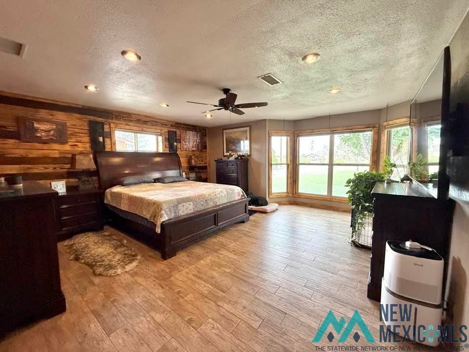5404 Sioux Road Carlsbad, NM 88220 - Photo 50 of 100 Spacious room featuring wood-finish flooring, a wood-paneled accent wall, a ceiling fan, recessed lighting, and a bay window configuration