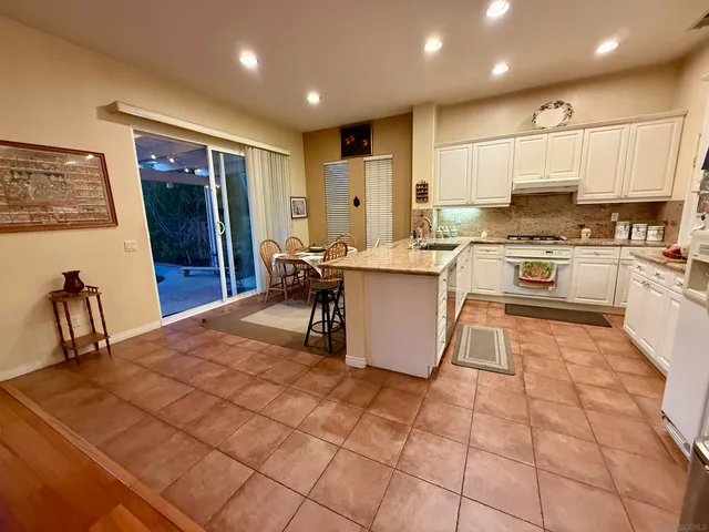 a kitchen with stainless steel appliances granite countertop a stove top oven a sink a dining table and chairs