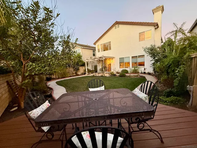a view of a patio with table and chairs potted plants with wooden floor and fence