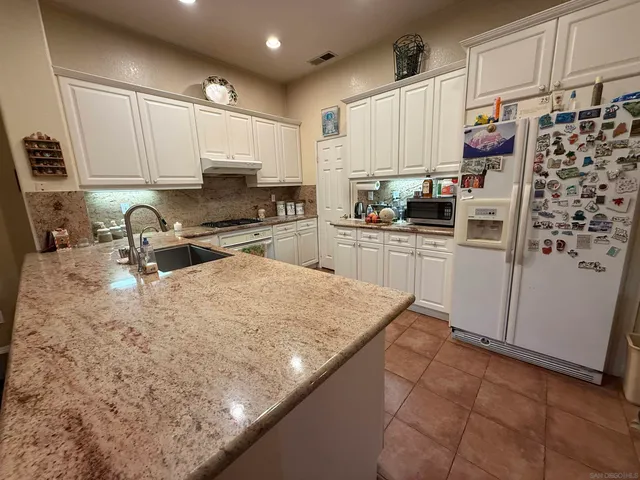a kitchen with stainless steel appliances granite countertop a sink refrigerator and cabinets