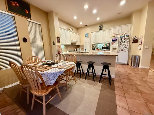 a kitchen with stainless steel appliances granite countertop table chairs sink and cabinets