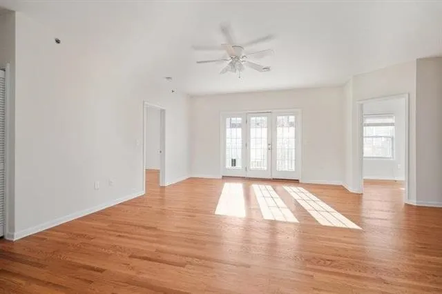 a view of an empty room with wooden floor and a window