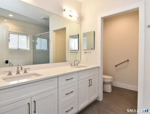 a bathroom with a double vanity sink toilet and a mirror