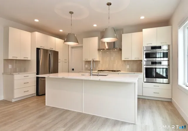 a kitchen with kitchen island a sink stainless steel appliances and cabinets