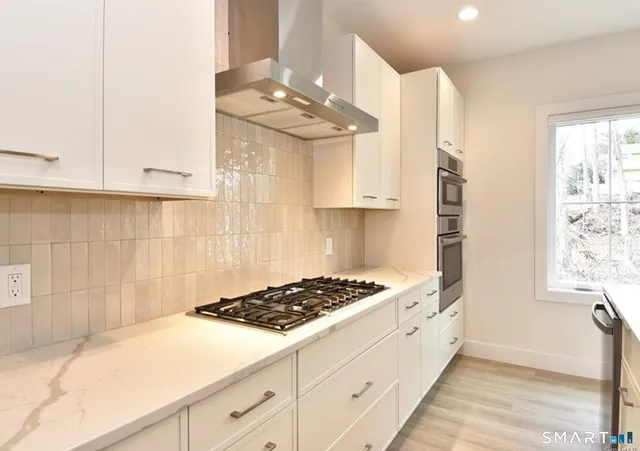 a kitchen with stainless steel appliances a sink a stove and white cabinets