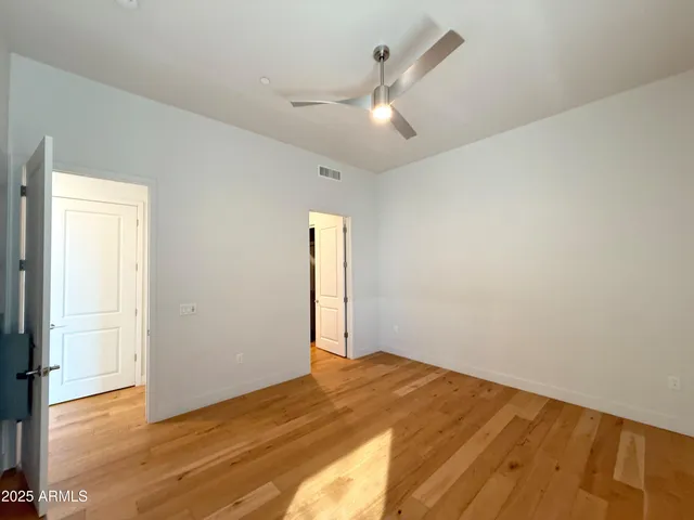 an empty room with wooden floor closet and windows