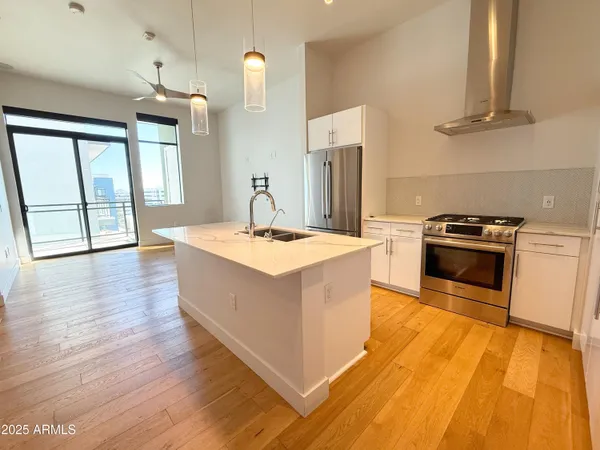 a kitchen with stainless steel appliances granite countertop a sink a stove and a wooden floors