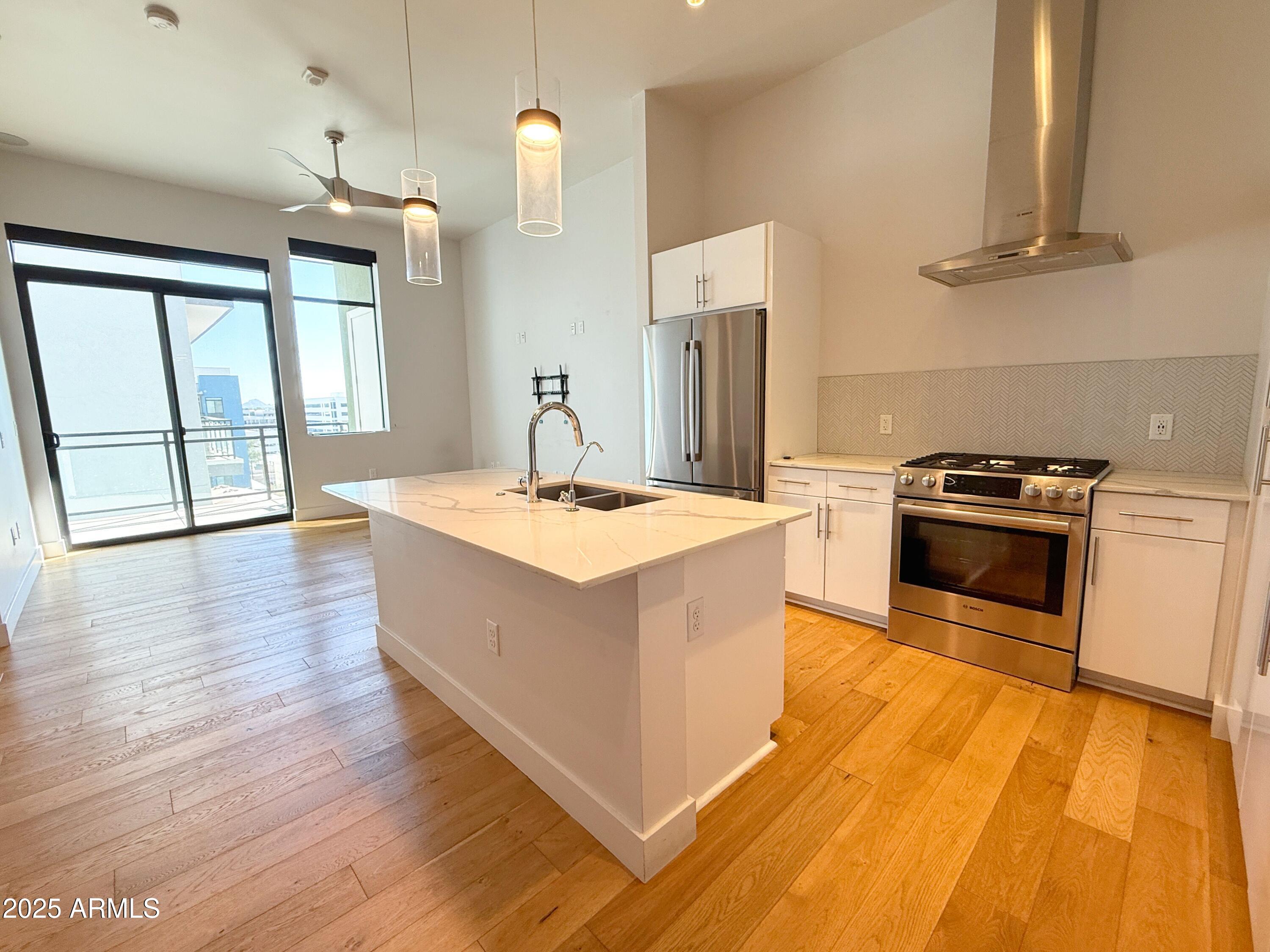 3131 North Central Avenue, Unit 7004 Phoenix, AZ 85012 - Photo 8 of 26 a kitchen with stainless steel appliances granite countertop a sink a stove and a wooden floors