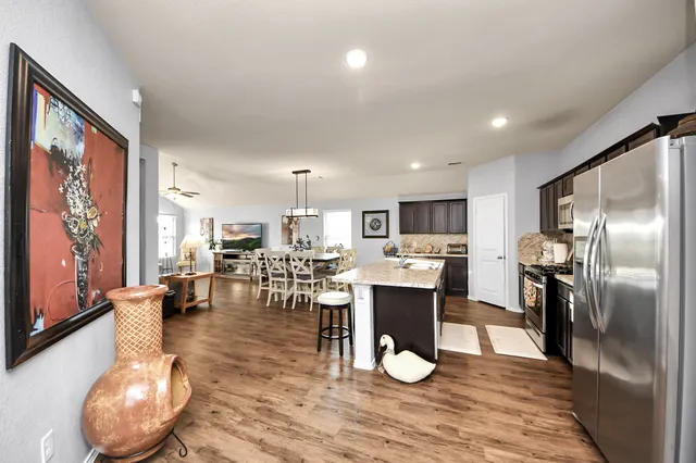 an open kitchen with granite countertop a refrigerator stove top oven dining table and chairs