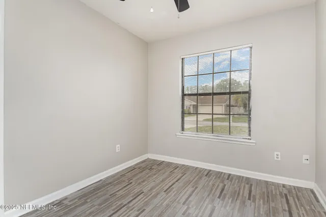 an empty room with wooden floor and windows