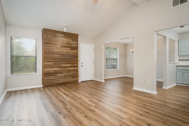 an empty room with wooden floor and windows