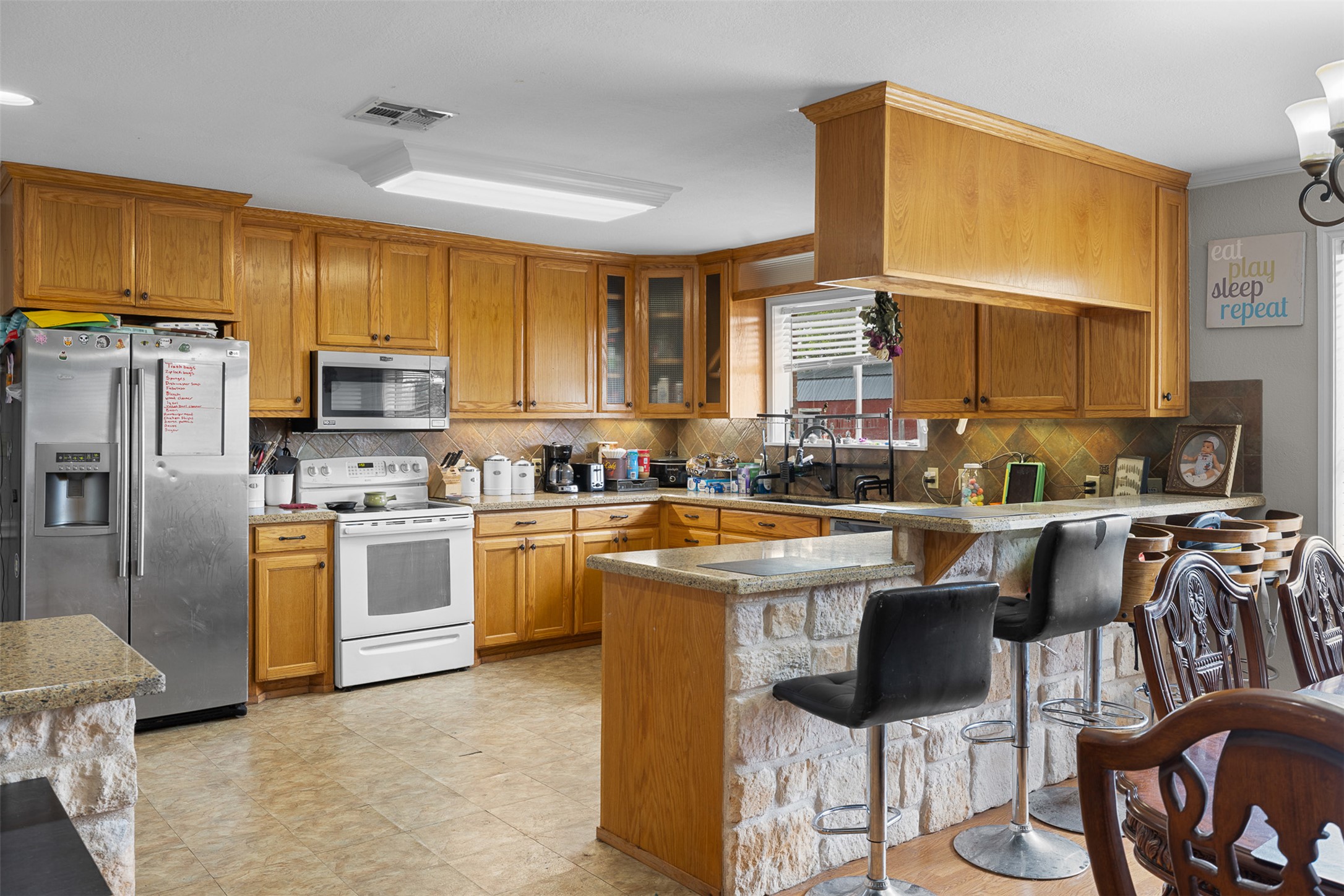 9765 State Park Road Lockhart, TX 78644 - Photo 24 of 40 a kitchen with stainless steel appliances granite countertop a stove a sink a refrigerator a dining table and chairs