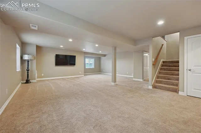 a view of an empty room with wooden floor and stairs