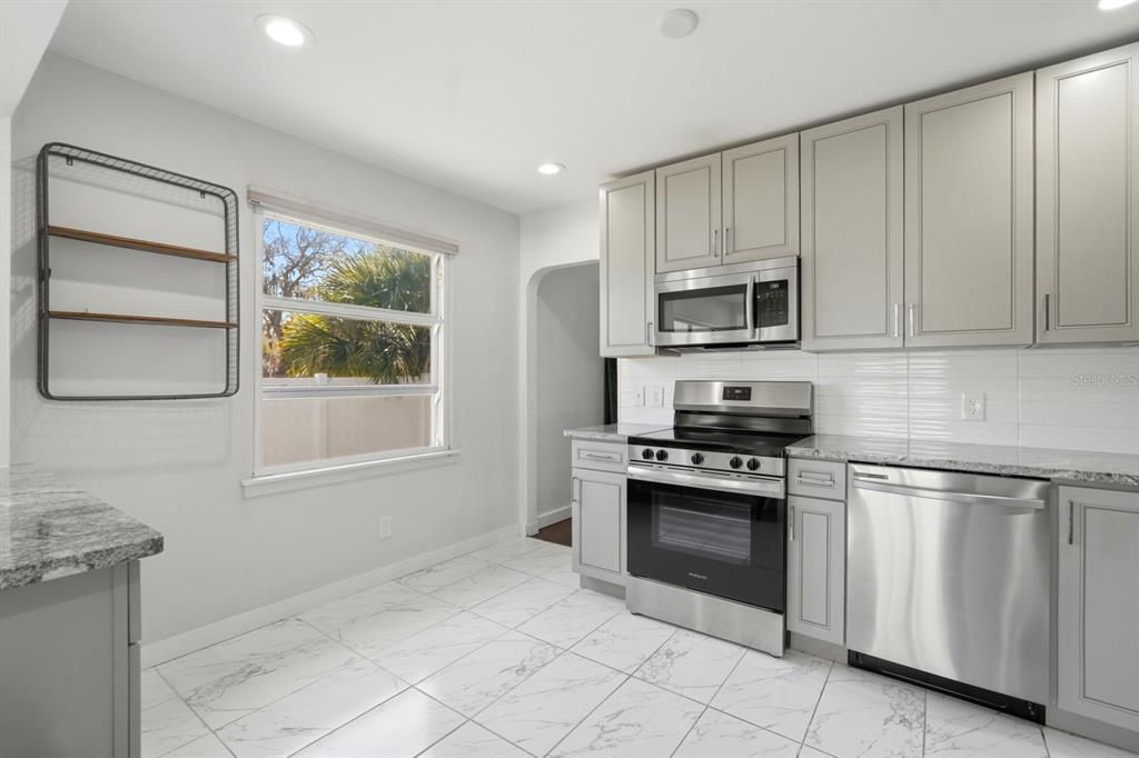 231 North Ridgewood Avenue Ormond Beach, FL 32174 - Photo 17 of 52 a kitchen with granite countertop white cabinets stainless steel appliances and a window