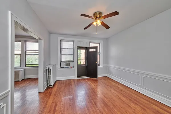 a view of an empty room with wooden floor and a window