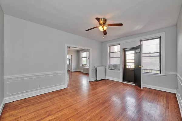 a view of an empty room with a window and wooden floor